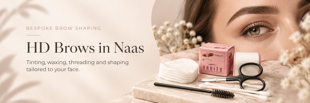 Promotional banner for HD Brows in Naas, featuring a close-up of a woman's eye and eyebrow, alongside cosmetic tools including a spoolie, scissors, and a pink box on a marble surface.