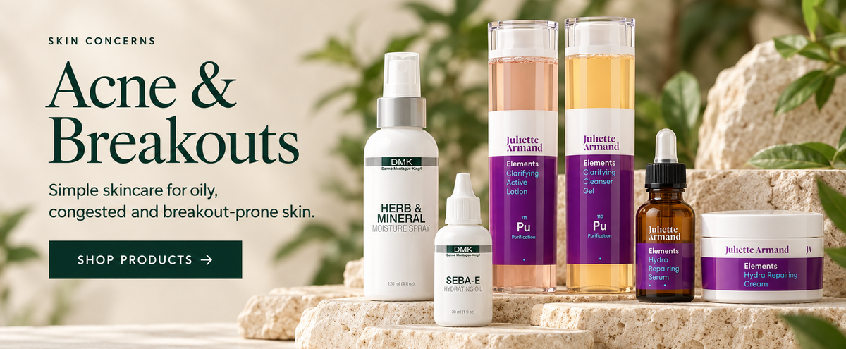 A set of skincare products arranged on natural stone slabs with a softly blurred outdoor background. The products include a white pump bottle labeled Herb & Mineral, a small white bottle labeled Seb-4, a white bottle labeled Piu, a clear bottle with pink liquid, a clear bottle with golden liquid, and a dark amber dropper bottle and a white jar with purple labels.